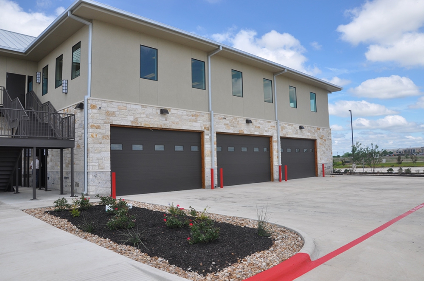 Outdoor photo of the side of a 2 story commercial building with metal stairway. 3 large bay garage doors to parking and drive. Commercial Construction Contracting by SB Thompson Construction in San Marcos, Texas