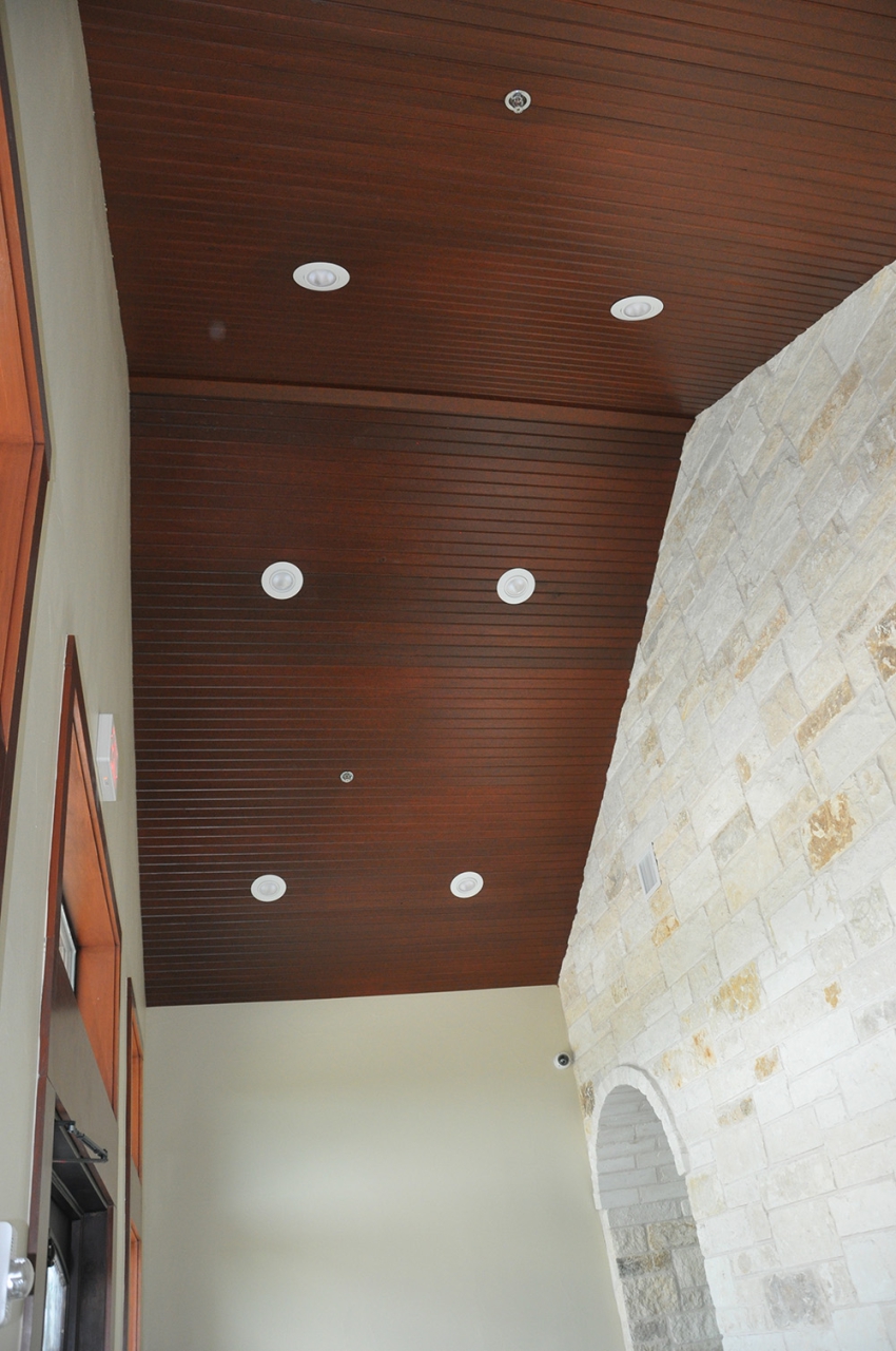 Construction Consulting and contracting in Central Texas. Dark wood panel ceiling with inset lighting, one wall limestone with archway to hall.