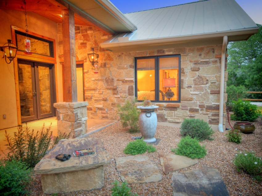 Entrance to a custom built ranch style home in Wimberley, Texas. Xeriscaped garden with native plants and stones.