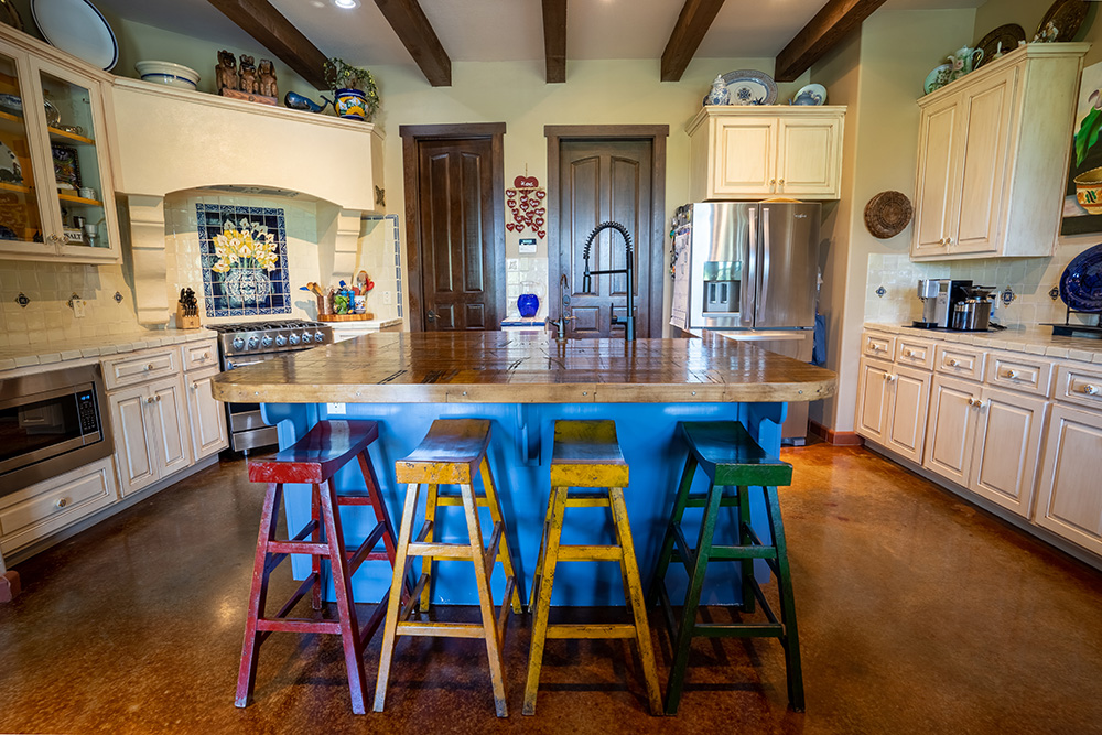 Custom kitchen counter made from antique rail car. Colorful wooden stools, and custom spanish tiles. Installed by S.B. Thompson Construction contractors in Central Texas.