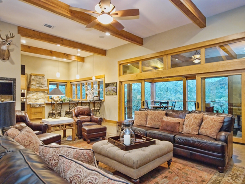 Living room and kitchen in a custom built ranch style home in Wimberley, Texas. Windows and sliding door opeing up the the Central Texas Hill Country.