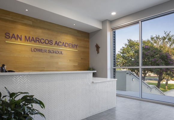 San Marcos Academy Lobby for lower school. Reception Desk with white tile, sign on a wood paneled wall. Built by Contractor SB Thompson Commercial Construction