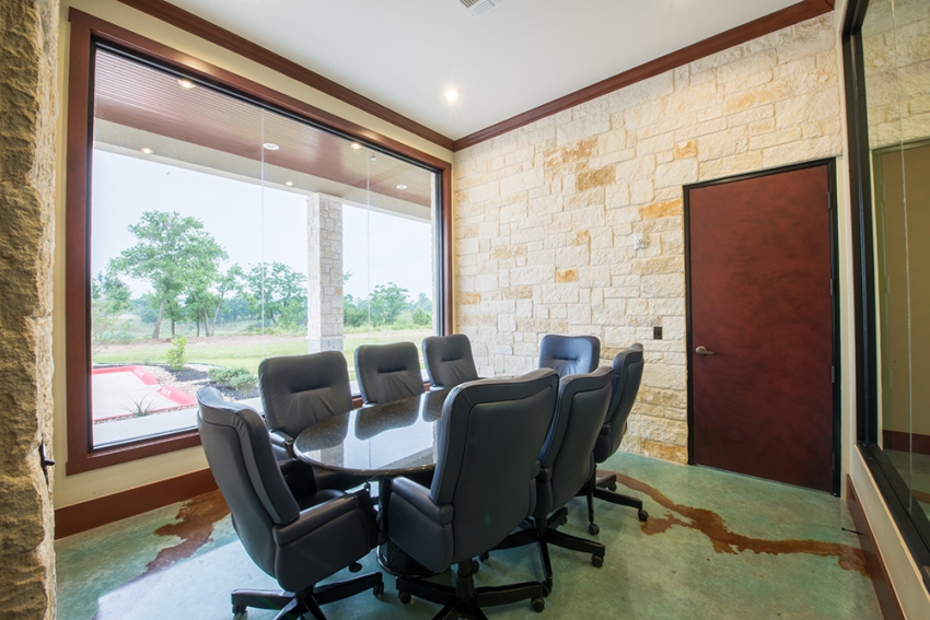 Commercial Construction boardroom, in Central Texas. Oval boardroom table with 8 chairs, stone walls gold apoxy floor. SB Thompson Construction Contractors.